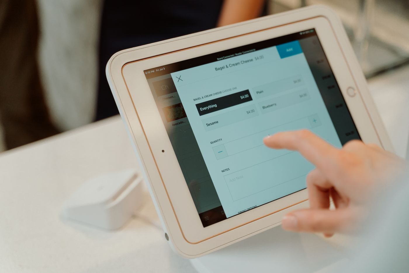 Mão operando sistema de vendas em tela sensível ao toque